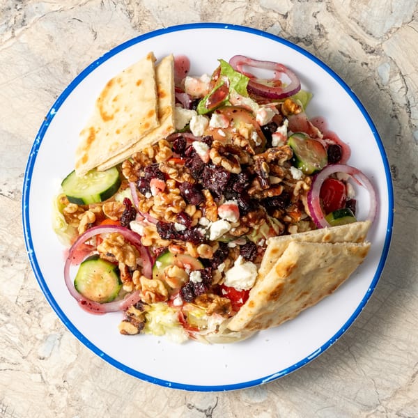 Krazy Greek salad with lettuce, cucumbers, red onion, feta, walnuts, dried cranberries, and pita bread.
